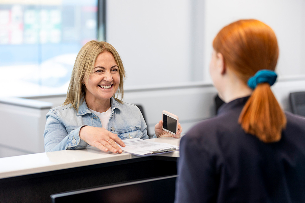 A female patient smiling at the reception desk as she checks in for her scan at Radiology Tasmania