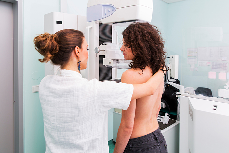 A mammography positions a patient at a mammography machine for a breast imaging examination.